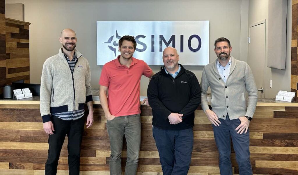 about the team at simio physical therapy. From left to right: Wesley, Nate, Rick and Craig stand in front of the front desk at SIMIO physical therapy clinic