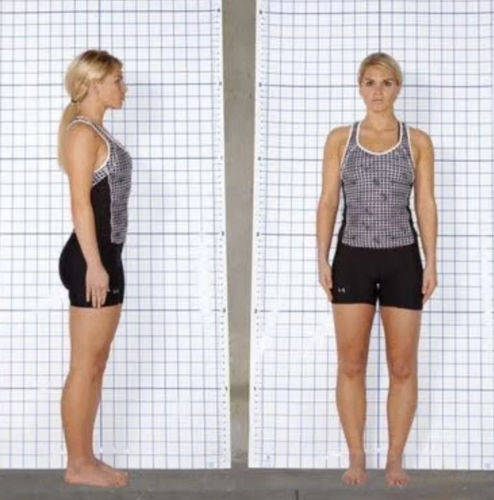 Belly breathing myths and posture. This image shows a woman standing in front of a grid background, providing a side view (left) and a front view (right). She is wearing a checkered tank top and black shorts. The grid background is used for posture analysis. She stands barefoot with her arms relaxed by her sides.